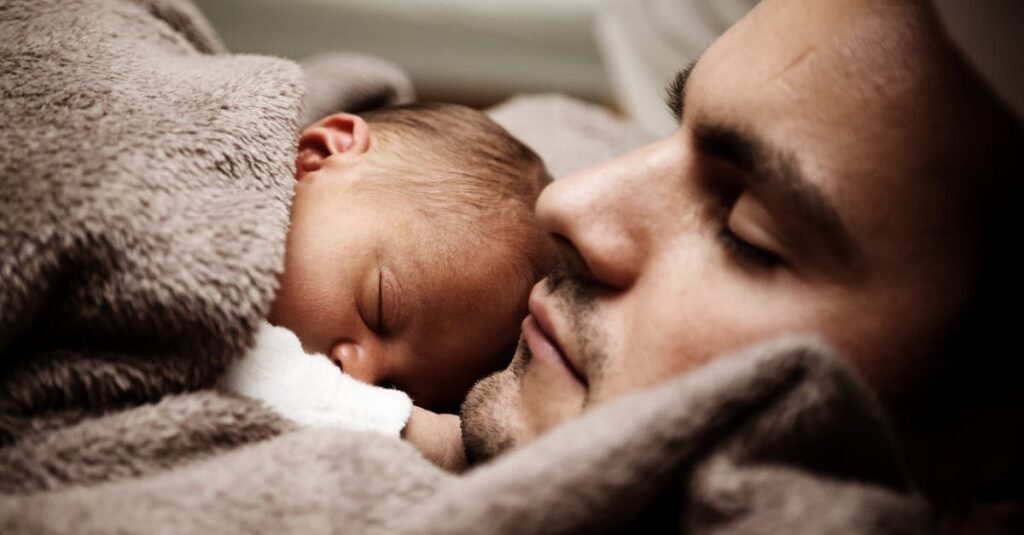 A touching close-up of a father and his baby peacefully napping together.